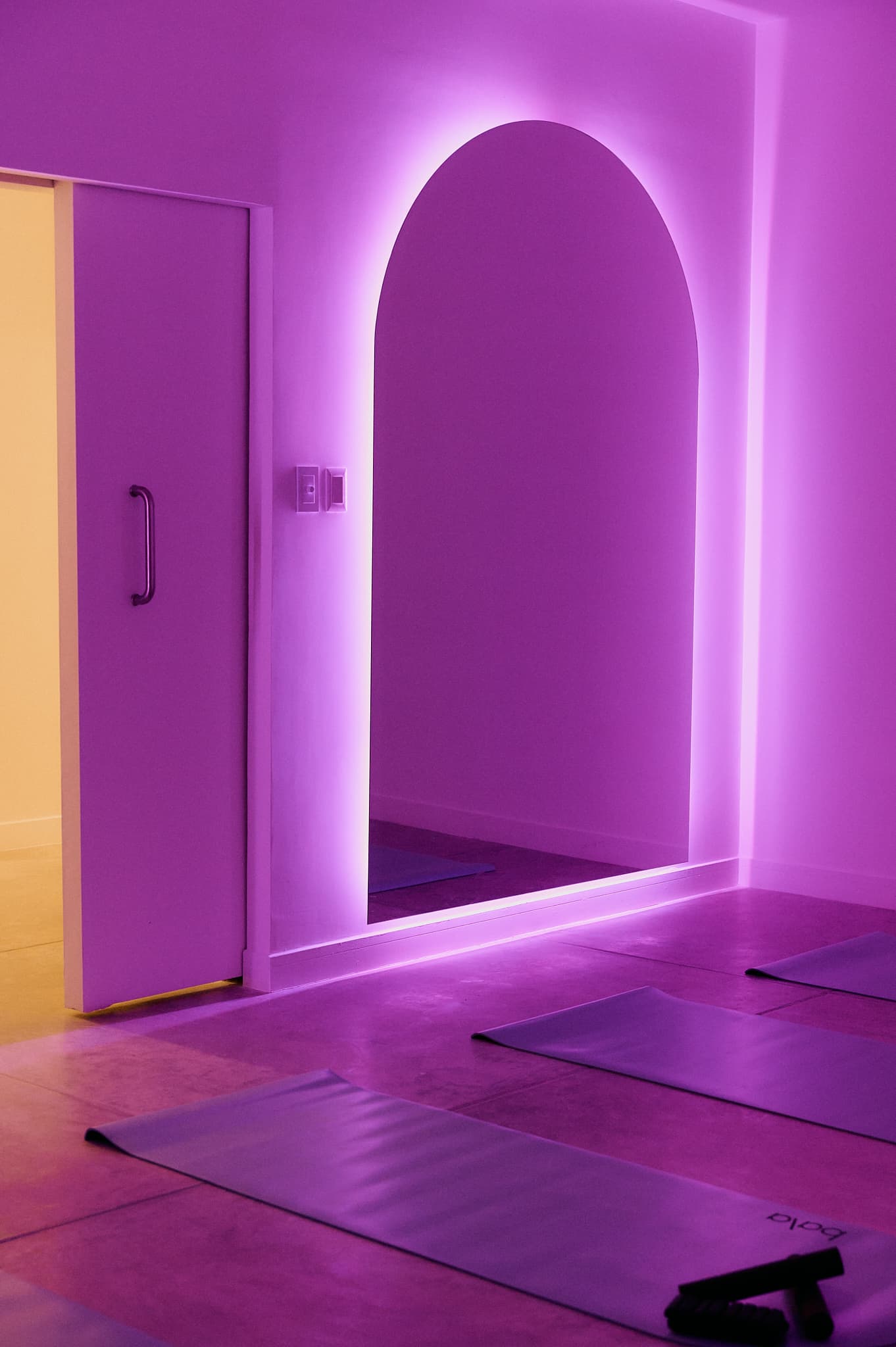 Sala de Pilates MAT AAURA con iluminación púrpura y arco decorativo