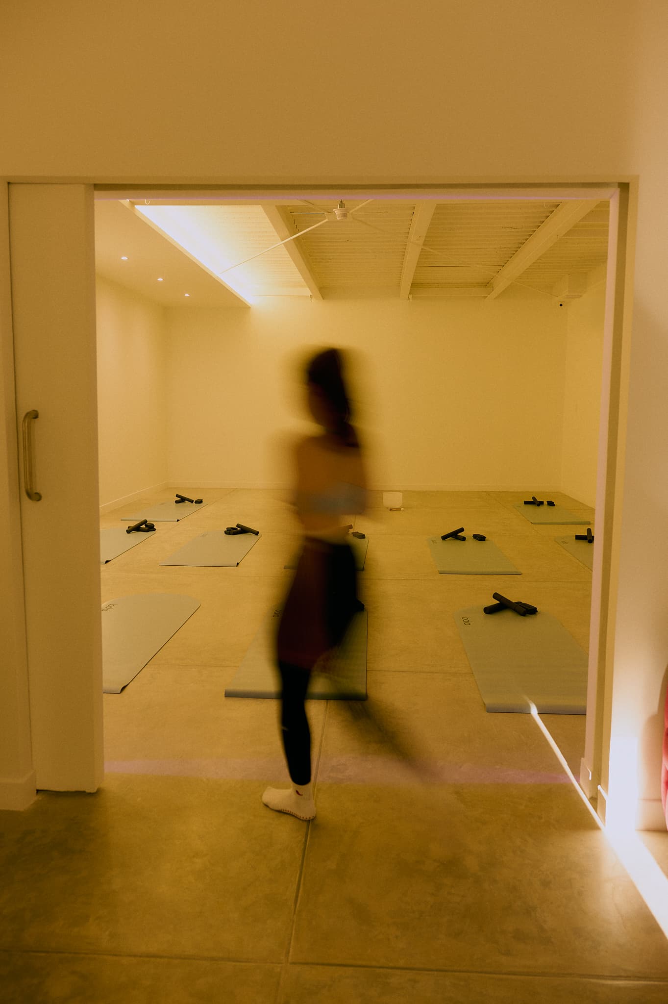 Sala de Pilates MAT AAURA con iluminación púrpura, colchonetas y proyección